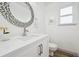 Bathroom with white vanity, silver hardware, designer mirror, and gray tone wood grain flooring at 748 Poppywood Pl, Highlands Ranch, CO 80126