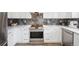 Close up on the stainless steel stove, stone backsplash and white cabinets, and modern appliances in the kitchen at 748 Poppywood Pl, Highlands Ranch, CO 80126