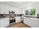 Bright kitchen with stainless steel oven, stone backsplash, white cabinets, modern appliances, and wood grain flooring at 748 Poppywood Pl, Highlands Ranch, CO 80126