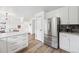 Open kitchen with large island, stainless steel refrigerator, microwave, white cabinets, and wood grain flooring at 748 Poppywood Pl, Highlands Ranch, CO 80126