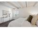 Bright bedroom with white ceiling beams, neutral walls, and a sunny window at 4801 E 9Th Ave # 402S, Denver, CO 80220