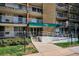 Apartment building entrance with a green awning, glass doors, a sidewalk, and some landscaping at 4801 E 9Th Ave # 402S, Denver, CO 80220