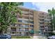 Multi-story condo building featuring private balconies and a welcoming entrance, surrounded by lush greenery and mature trees at 4801 E 9Th Ave # 402S, Denver, CO 80220