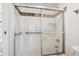 Close-up of a shower with glass doors and white tiled walls with a decorative tile border at 4801 E 9Th Ave # 402S, Denver, CO 80220