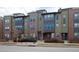 A view of the exterior of modern townhomes with brick and neutral color siding, plus well-maintained landscaping at 8722 E 47Th Ave, Denver, CO 80238