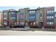 A view of the exterior of modern townhomes with brick and neutral color siding, plus well-maintained landscaping at 8722 E 47Th Ave, Denver, CO 80238