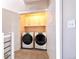 Well-lit laundry room features two modern appliances and built in storage with white cabinets at 8722 E 47Th Ave, Denver, CO 80238