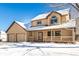 Two-story house with beige siding, double garage, and a covered porch in the snow at 1506 Maple Dr, Berthoud, CO 80513