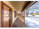 Wooden front porch with railing, entry door, and view of a tree-lined street at 1506 Maple Dr, Berthoud, CO 80513