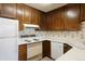 Traditional kitchen with wood cabinets, white appliances, floral wallpaper, and laminate countertops at 3470 S Poplar St # 401, Denver, CO 80224