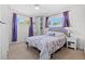 Cozy bedroom with large windows, purple curtains, ceiling fan and a comfortable bed with floral patterned bedding at 11320 Irma Dr, Northglenn, CO 80233
