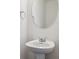 Close-up of powder room featuring a white pedestal sink, a round mirror, and modern fixtures at 4028 N Rome St, Aurora, CO 80019