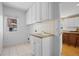 Functional laundry room with white cabinets, a utility sink, tile flooring, and a bright window at 7226 Dove Ct, Parker, CO 80134