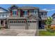 Beautiful two-story home with a three-car garage, stone accents, and a well-maintained front lawn at 14763 Pepper Pike Pl, Parker, CO 80134