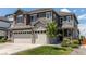 Charming two-story home with gray siding, stone accents, three-car garage and a young tree in the yard at 14763 Pepper Pike Pl, Parker, CO 80134