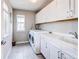 Bright laundry room with modern washer and dryer, sink, white cabinets, and window at 14763 Pepper Pike Pl, Parker, CO 80134