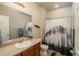 Well-lit bathroom featuring a shower with decorative curtain and a wood vanity with sink at 6434 N Ensenada Ct, Aurora, CO 80019