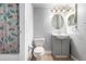 Bathroom with a toilet, sink, vanity, round mirror, and shower with butterfly curtain at 10211 Ura Ln # 8-102, Thornton, CO 80260