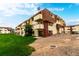 The building has orange and beige tones with balconies and a large grassy lawn at 10211 Ura Ln # 8-102, Thornton, CO 80260