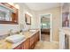 Bathroom with double sinks and granite counters with a view to the bedroom at 12421 W Fair Dr, Littleton, CO 80127