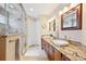 Bathroom featuring double sinks with granite countertops, a glass shower, and neutral tile flooring at 12421 W Fair Dr, Littleton, CO 80127