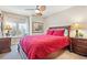 Bedroom with ceiling fan, natural light, and a plush red bedspread at 12421 W Fair Dr, Littleton, CO 80127