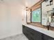 Modern bathroom with dual sinks, black hardware, wood-look accents, and a window view at 22 Rangeview Dr, Wheat Ridge, CO 80215