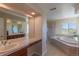 Bright bathroom features a double sink vanity, soaking tub, and glass enclosed shower at 2339 Elkhorn St, Parker, CO 80138