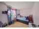 Bedroom with light pink walls, window, bed with plush toys, and desk at 1024 S Mobile St, Aurora, CO 80017