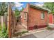 Side exterior of brick home showing the driveway, wood fence, and some greenery at 3321 W 29Th Ave, Denver, CO 80211