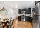Open kitchen and dining area featuring stainless steel appliances, dark cabinets, and stylish pendant lighting at 3321 W 29Th Ave, Denver, CO 80211