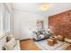 Bright living room featuring exposed brick, hardwood floors, a cozy couch, and a large window at 3321 W 29Th Ave, Denver, CO 80211