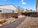 Landscaped backyard with a wooden wishing well surrounded by rock and a path leading to a gated fence at 353 Zuniga St, Brighton, CO 80601
