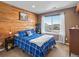 Cozy bedroom features a wood accent wall, large window, and a comfortable blue-and-white bedspread at 353 Zuniga St, Brighton, CO 80601