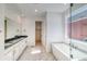 Modern bathroom with double vanity, marble floors, and a freestanding tub by the window with neighborhood views at 39555 Gwinett Cir, Elizabeth, CO 80107
