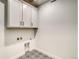 Functional laundry room with overhead cabinets, patterned floor tiles, and clean, bright finishes at 39555 Gwinett Cir, Elizabeth, CO 80107