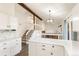 Modern white kitchen showcasing stone backsplash, quartz countertop, and open layout to the living area with fireplace at 3915 E Jamison Pl, Centennial, CO 80122