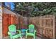 Cozy patio area with vibrant green Adirondack chairs, complemented by a charming wooden fence and lush trees at 10836 W Evans Ave # 32, Lakewood, CO 80227