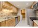 Well-lit kitchen with stainless steel appliances, tile backsplash, and light wood cabinets at 3550 S Harlan St # 259, Denver, CO 80235