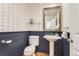 Charming powder room featuring nautical wallpaper, blue wainscoting, pedestal sink, and a decorative mirror at 2163 S Grant St, Denver, CO 80210