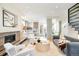 Bright, open living room with hardwood floors, a modern fireplace, and white armchairs flowing into the kitchen at 2659 S Cherokee St, Denver, CO 80223