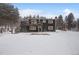 Two-story home with a deck and snowy yard surrounded by pine trees at 26788 Richmond Hill Rd, Conifer, CO 80433