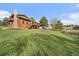 Spacious backyard featuring a wooden deck and balcony, lush green lawn, and a wooden fence at 8072 Windwood Way, Parker, CO 80134