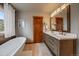 Bright bathroom features a soaking tub and double sink vanity with modern fixtures at 8072 Windwood Way, Parker, CO 80134
