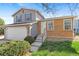 Two-story home with neutral siding, brick accents, two-car garage, and steps leading to the entrance at 3732 S Halifax St, Aurora, CO 80013