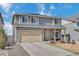 Two-story gray home with a beige two car garage and an easy to maintain lawn on a bright sunny day at 5251 Truckee St, Denver, CO 80249