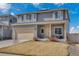 Two-story gray home with a beige two car garage and a partially dormant lawn on a bright sunny day at 5251 Truckee St, Denver, CO 80249