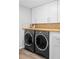 Bright laundry room with white cabinets, wood countertops, and modern washer and dryer units at 11354 Allendale Dr, Arvada, CO 80004