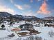 Aerial view of a gray home in a snow-covered area with mountain views under a colorful sky at 931 Forest View Rd, Monument, CO 80132