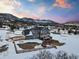 Aerial view of a home in a snow-covered landscape with a fenced yard, play set, and mountain views at 931 Forest View Rd, Monument, CO 80132